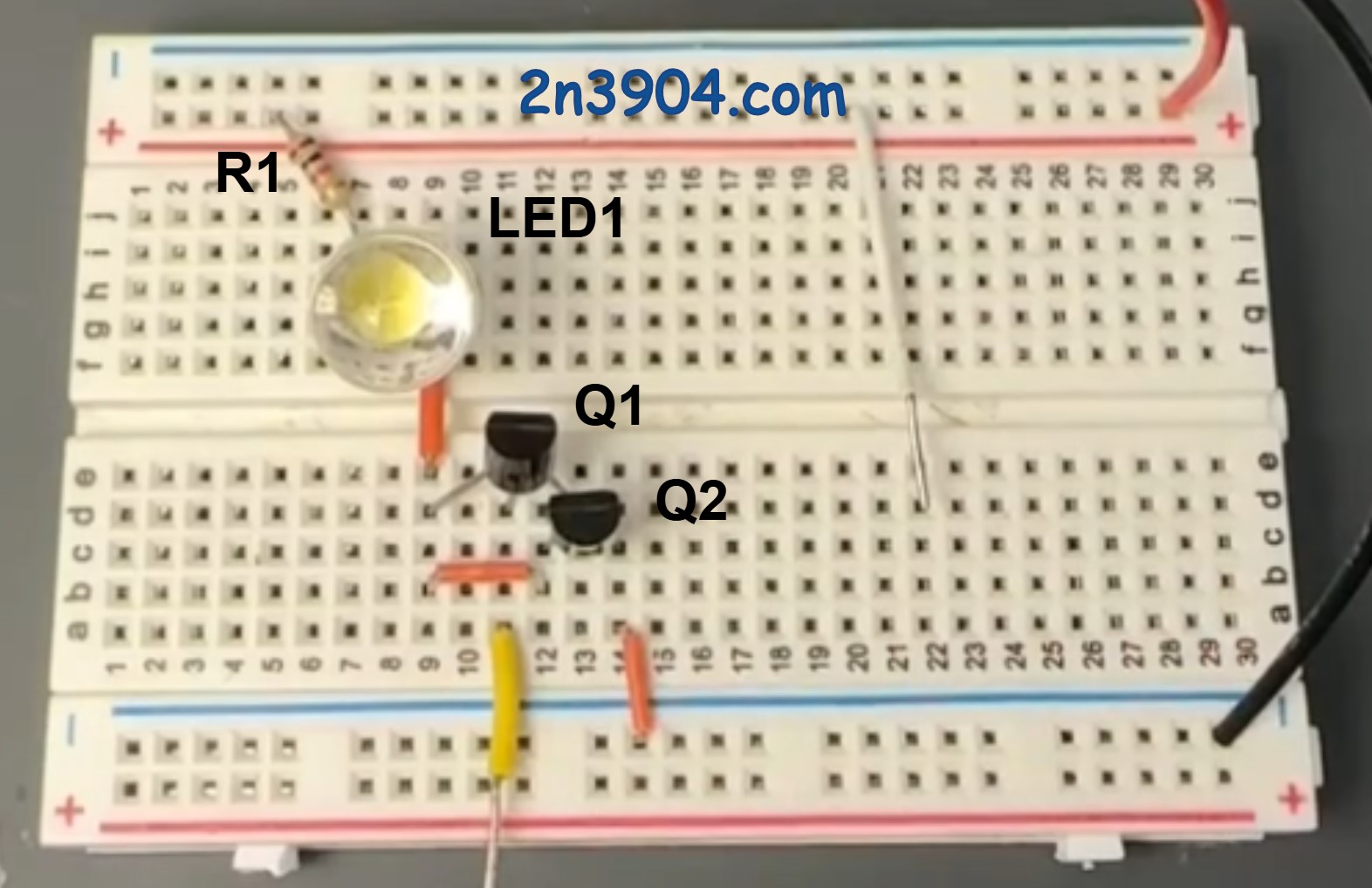 Close up view of two 2N3904 transistors wired as a Darlington pair on a breadboard for a finger activated LED circuit